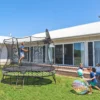 Děti si hrají na zahradě a skákají na trampolíně