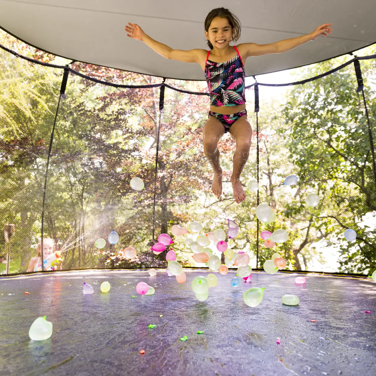 Dívka skáče na trampolíně Springfree pod sluneční clonou